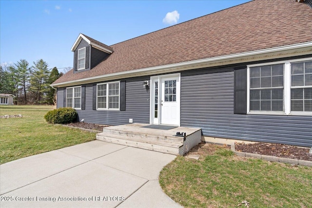 view of front facade with roof with shingles and a front yard