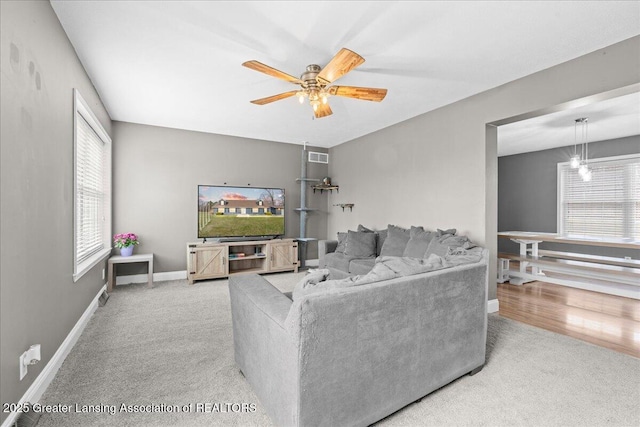 carpeted living room featuring baseboards, a ceiling fan, and visible vents