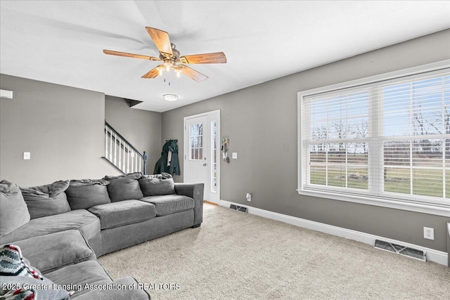 living room featuring stairs, visible vents, and carpet