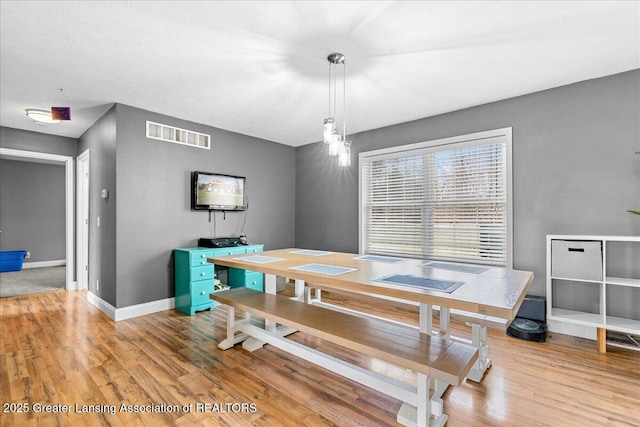 dining area with baseboards, visible vents, and light wood-style flooring