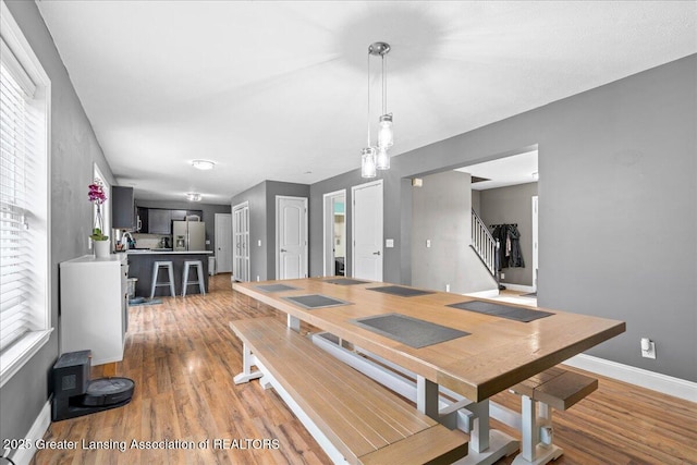 dining space with stairway, light wood finished floors, and baseboards