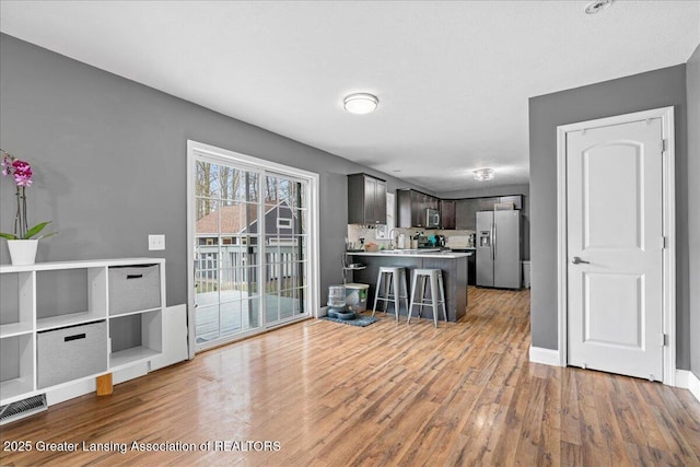 kitchen with a peninsula, wood finished floors, visible vents, and appliances with stainless steel finishes