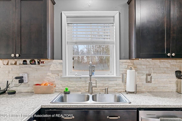 kitchen with dark brown cabinets, stainless steel dishwasher, a sink, and backsplash