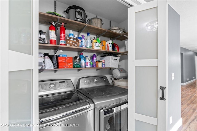 clothes washing area with baseboards, wood finished floors, independent washer and dryer, and laundry area
