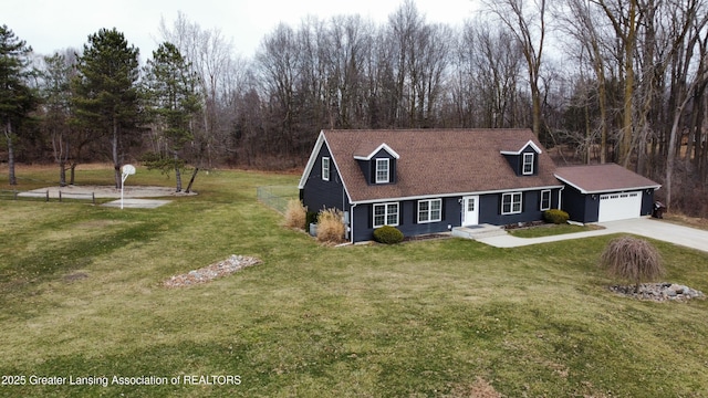 new england style home featuring an attached garage, roof with shingles, a front yard, and concrete driveway