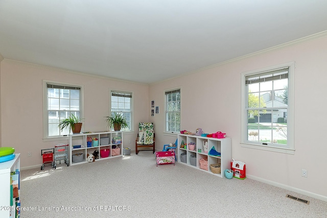recreation room featuring crown molding, carpet flooring, visible vents, and a wealth of natural light
