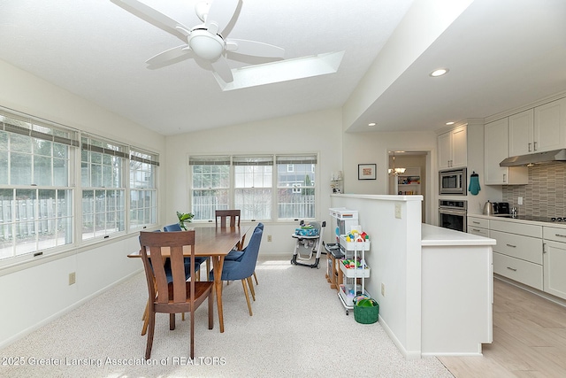 dining area with a ceiling fan, baseboards, recessed lighting, and vaulted ceiling with skylight