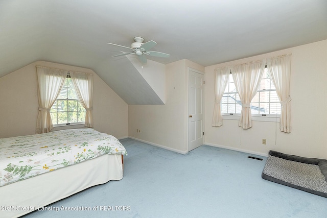 carpeted bedroom featuring visible vents, baseboards, lofted ceiling, and multiple windows