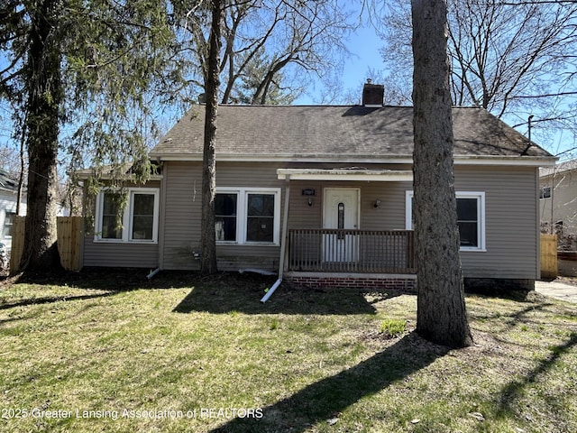 1909 W Holmes Rd, Lansing, MI 48910 - bungalow-style home with a chimney, covered porch, fence, a front yard, and roof with shingles