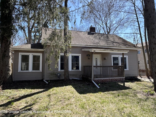 1909 W Holmes Rd, Lansing, MI 48910 - view of front of home with a shingled roof, a front lawn, and a chimney