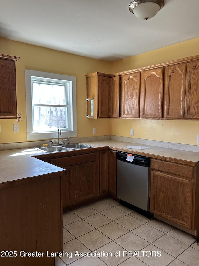 1909 W Holmes Rd, Lansing, MI 48910 - kitchen with stainless steel dishwasher, a sink, brown cabinets, and light tile patterned floors