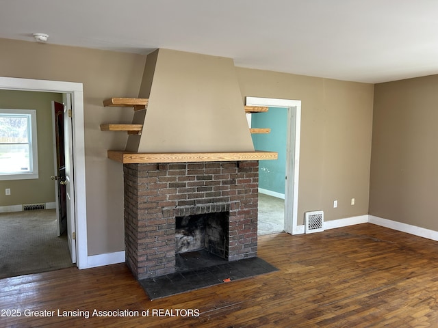 1909 W Holmes Rd, Lansing, MI 48910 - unfurnished living room with baseboards, wood finished floors, visible vents, and a fireplace