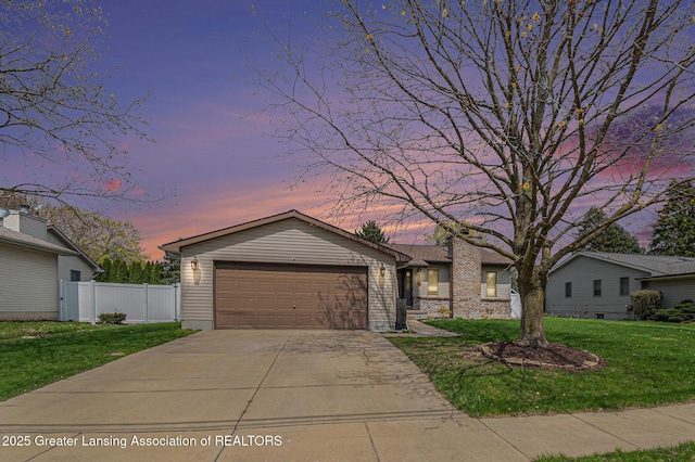 ranch-style house featuring concrete driveway, a lawn, an attached garage, and fence