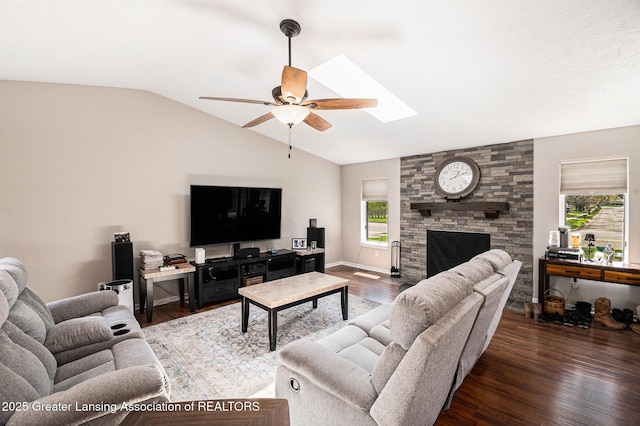 living room with wood finished floors, ceiling fan, lofted ceiling with skylight, and a fireplace