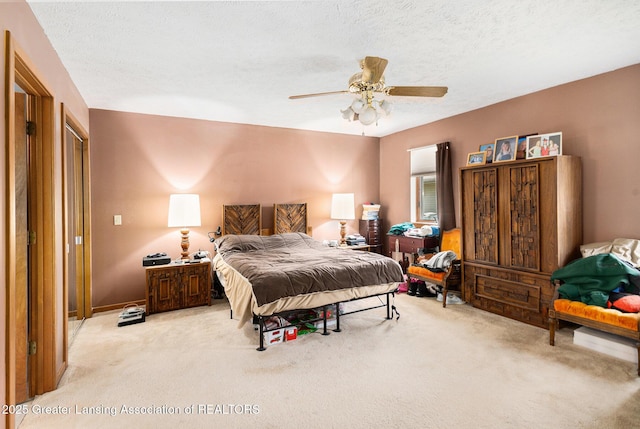 bedroom featuring a textured ceiling, ceiling fan, and light carpet