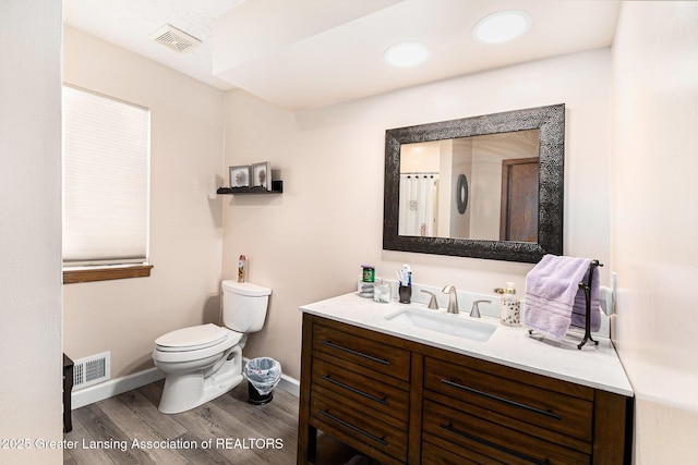 bathroom featuring vanity, toilet, visible vents, baseboards, and wood finished floors