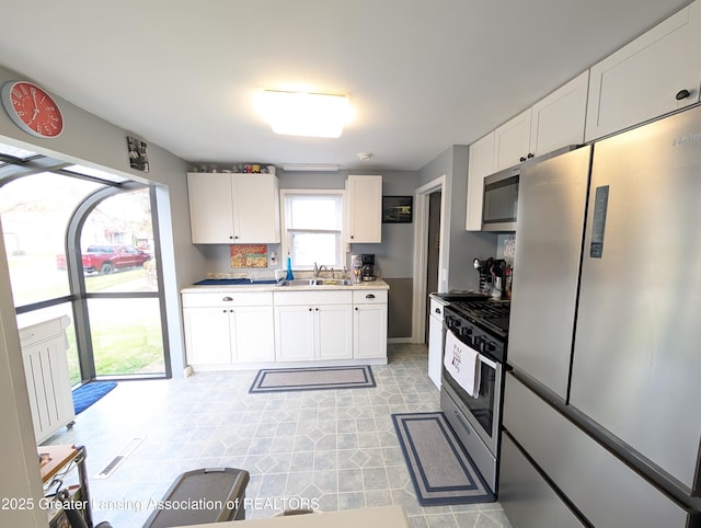 kitchen featuring light countertops, appliances with stainless steel finishes, white cabinetry, and a sink