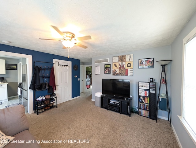 living area with light carpet, a wealth of natural light, ceiling fan, and visible vents