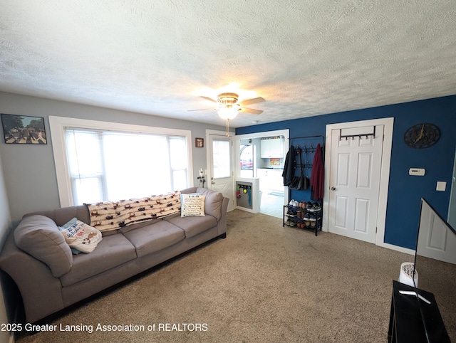 living room featuring carpet floors, a textured ceiling, baseboards, and ceiling fan