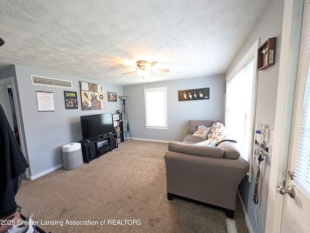 living room with visible vents, carpet floors, baseboards, a textured ceiling, and ceiling fan