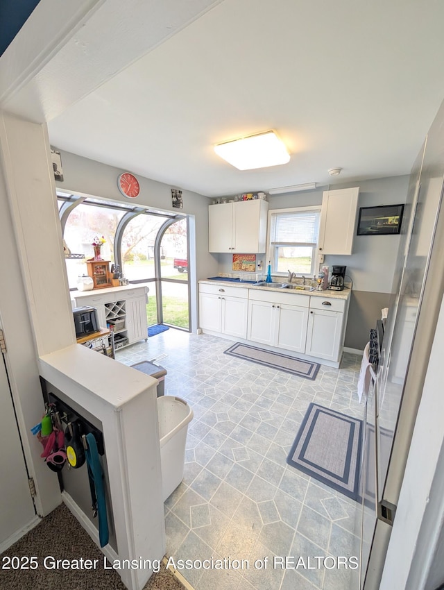 kitchen with light countertops, white cabinetry, and a sink