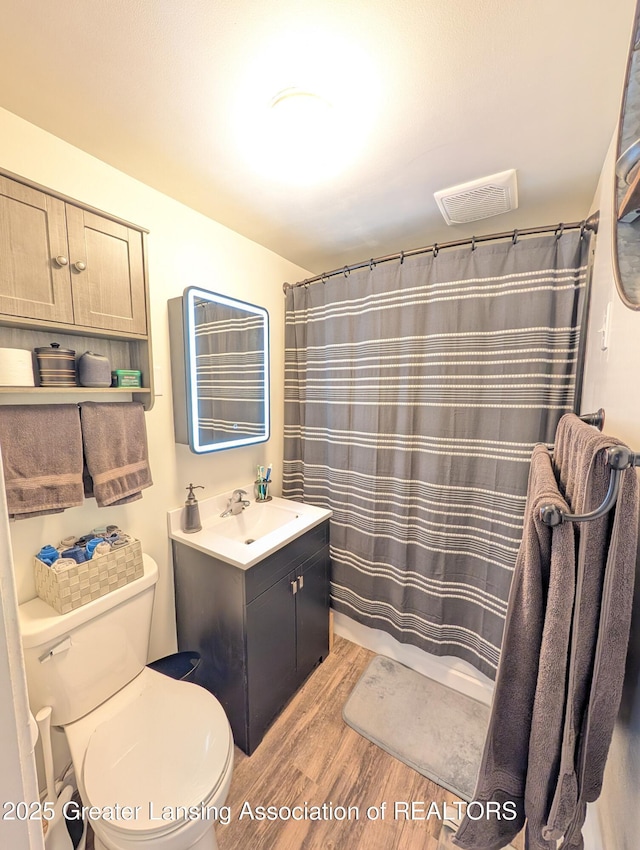 bathroom with wood finished floors, vanity, curtained shower, toilet, and visible vents