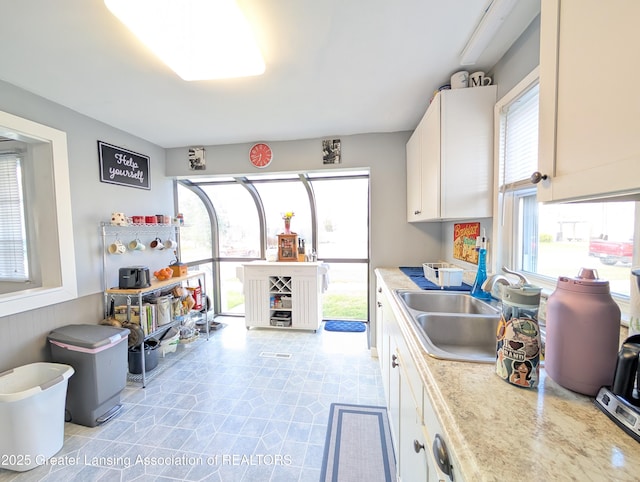 kitchen featuring white cabinets, a sink, and light countertops
