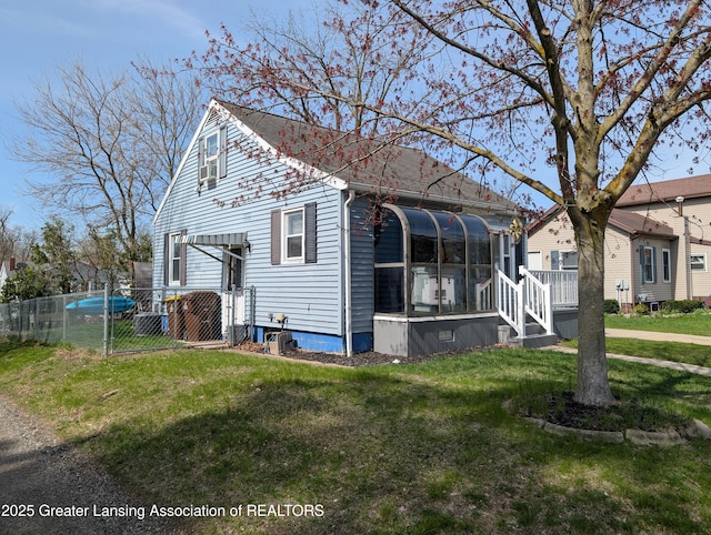 view of front of property featuring a front lawn, a sunroom, and fence