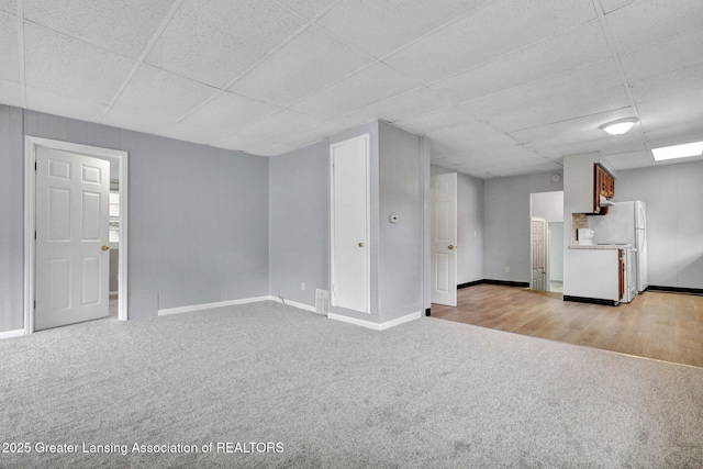 218 W Thomas St, Lansing, MI 48906 - unfurnished living room featuring light carpet, baseboards, and a drop ceiling