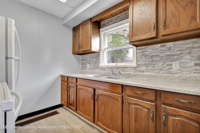 218 W Thomas St, Lansing, MI 48906 - kitchen with a sink, decorative backsplash, light countertops, and brown cabinets