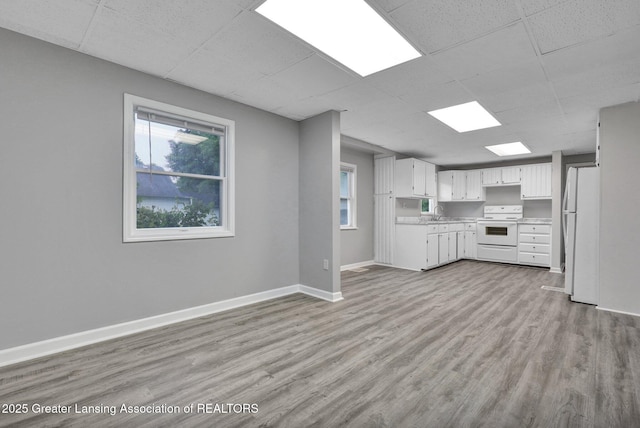 425 Filley St, Lansing, MI 48906 - kitchen featuring white appliances, a drop ceiling, light countertops, light wood-style floors, and baseboards