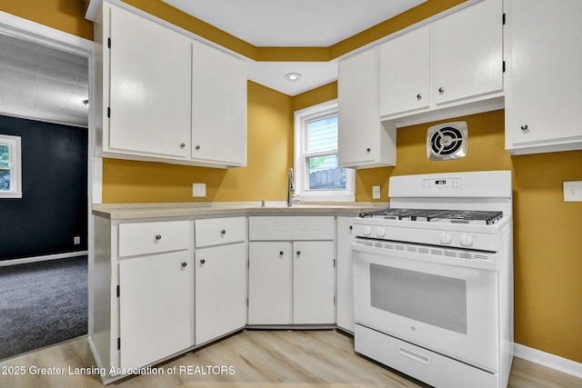 908 Larned St, Lansing, MI 48912 - kitchen featuring white gas range, a sink, light countertops, white cabinetry, and light wood-style floors