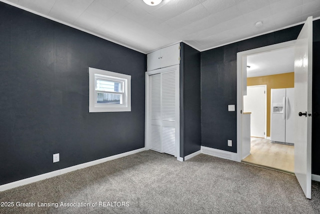 908 Larned St, Lansing, MI 48912 - unfurnished bedroom featuring white fridge with ice dispenser, carpet floors, a closet, and baseboards