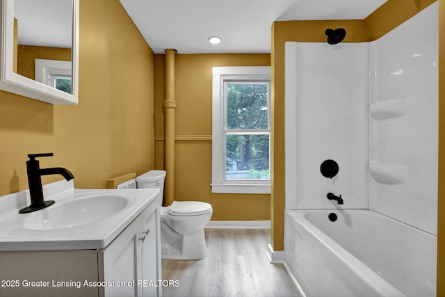 908 Larned St, Lansing, MI 48912 - full bath featuring wood finished floors, toilet, vanity, baseboards, and tub / shower combination