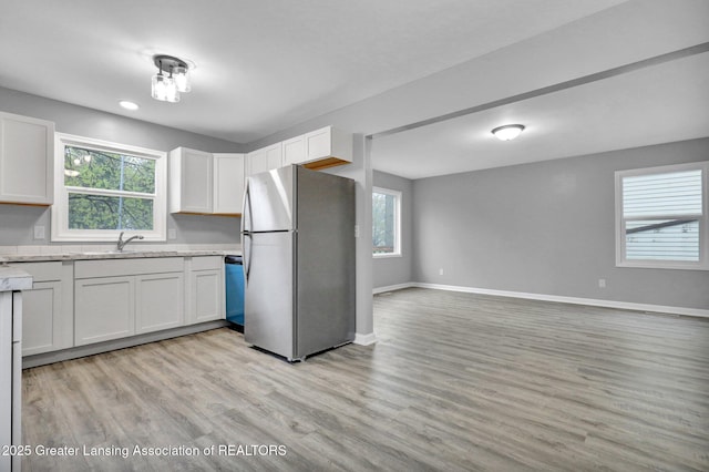 2619 Schippell St, Holt, MI 48842 - kitchen with a sink, baseboards, freestanding refrigerator, light wood finished floors, and open floor plan