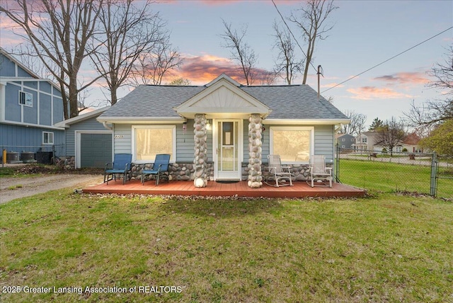 exterior space featuring a lawn, aphalt driveway, stone siding, fence, and a wooden deck
