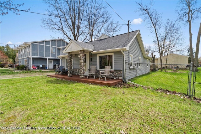 split level home with a wooden deck, a shingled roof, a front lawn, and fence