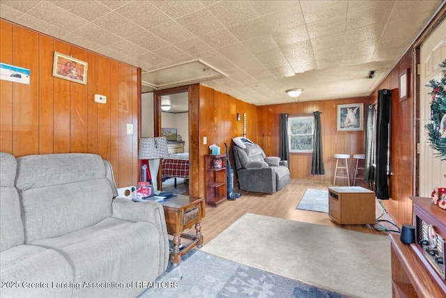 living area with wooden walls, wood finished floors, and visible vents
