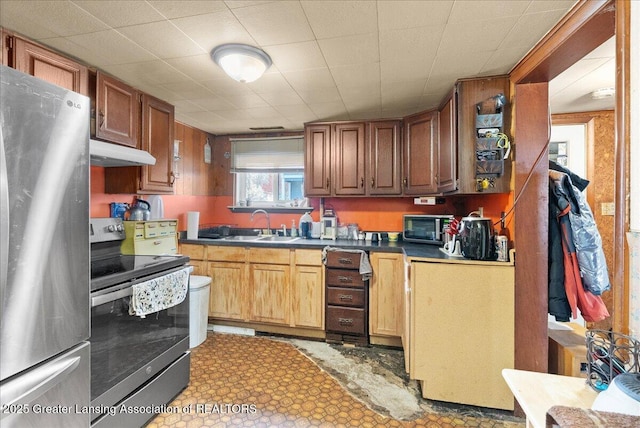kitchen with under cabinet range hood, dark countertops, stainless steel appliances, and a sink