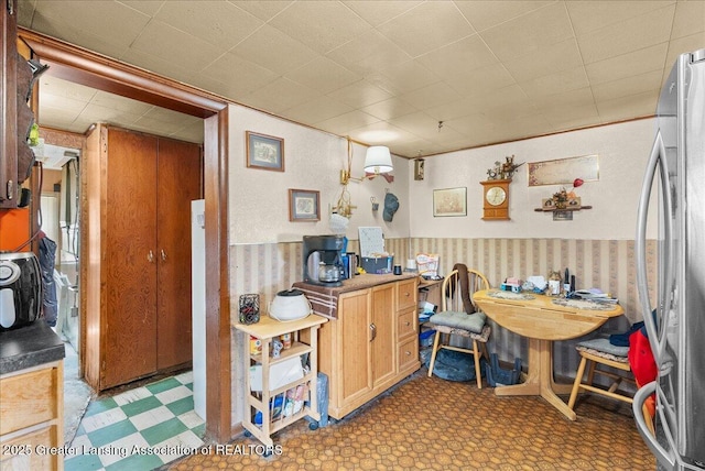 dining space with wallpapered walls, tile patterned floors, and a wainscoted wall