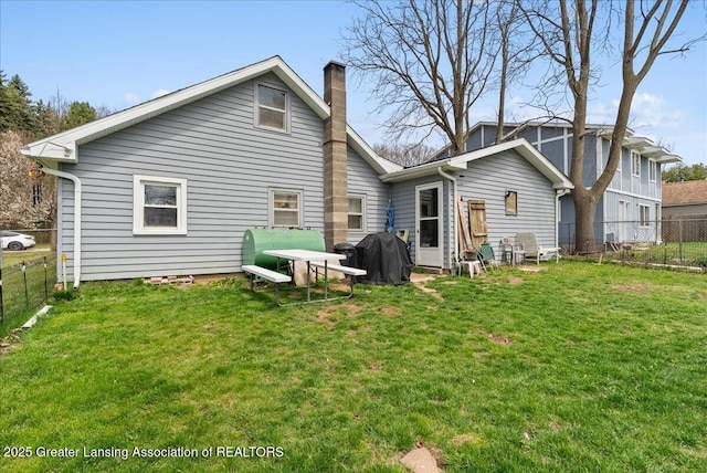 rear view of house featuring a chimney, a fenced backyard, and a lawn