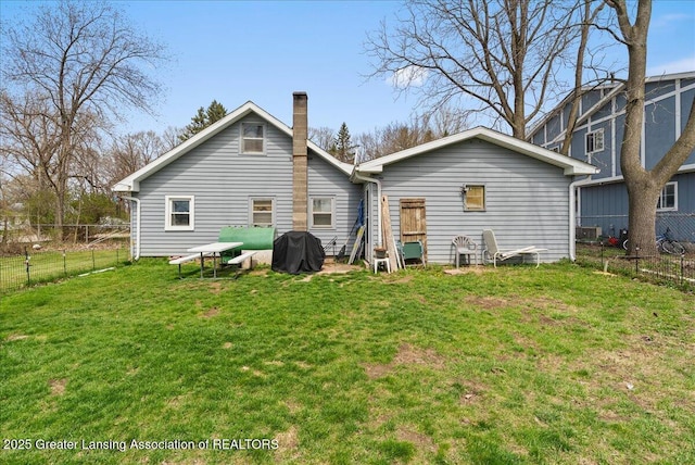 rear view of house with a lawn, a fenced backyard, and a chimney