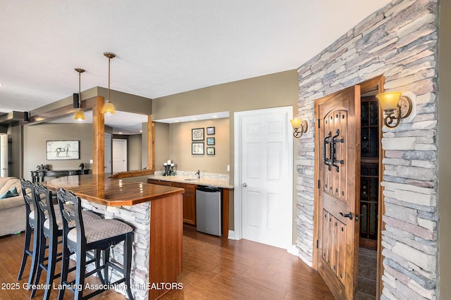 12714 Ospreys Way, Dewitt, MI 48820 - kitchen with light stone counters, brown cabinetry, decorative light fixtures, dark wood-style flooring, and open floor plan
