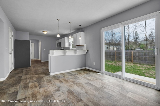 12001 Bryde Dr, Rives Junction, MI 49277 - kitchen featuring decorative light fixtures, a peninsula, baseboards, and dark wood-style floors