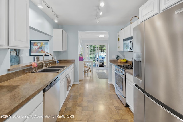 kitchen featuring track lighting, white cabinetry, stainless steel appliances, and a sink