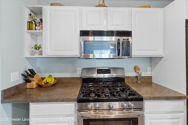 kitchen with dark countertops, open shelves, appliances with stainless steel finishes, and white cabinetry