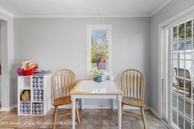 dining space with stone finish flooring, ornamental molding, and baseboards