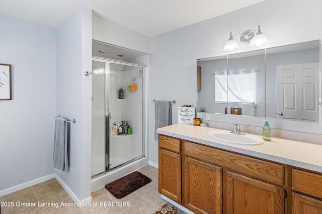 bathroom with a stall shower, vanity, tile patterned flooring, and baseboards