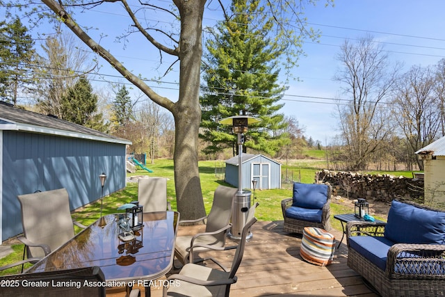 wooden deck featuring an outbuilding, a lawn, a storage unit, and a playground