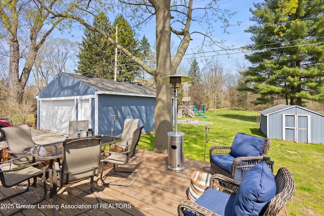 view of patio / terrace featuring an outbuilding, a detached garage, outdoor dining space, and a playground